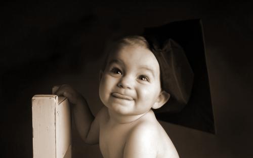 ребенок с беретом обнимает стул и улыбается