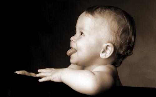 малыш улыбается и показывает язык