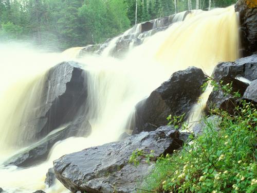 водопад Pigeon Falls в Миннесоте и черные гранитные камни с желтой водой